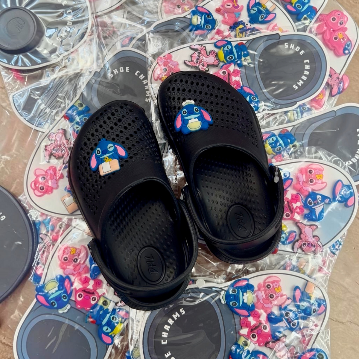 TipTop Retail black clog shoes decorated with cute blue character rubber charms on a background of charm packs