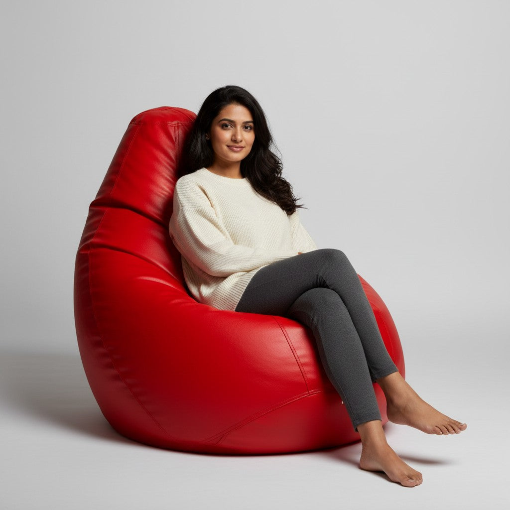 A woman sitting comfortably on a vibrant red TipTop Retail tear-drop bean bag chair cover in a bright studio setting.