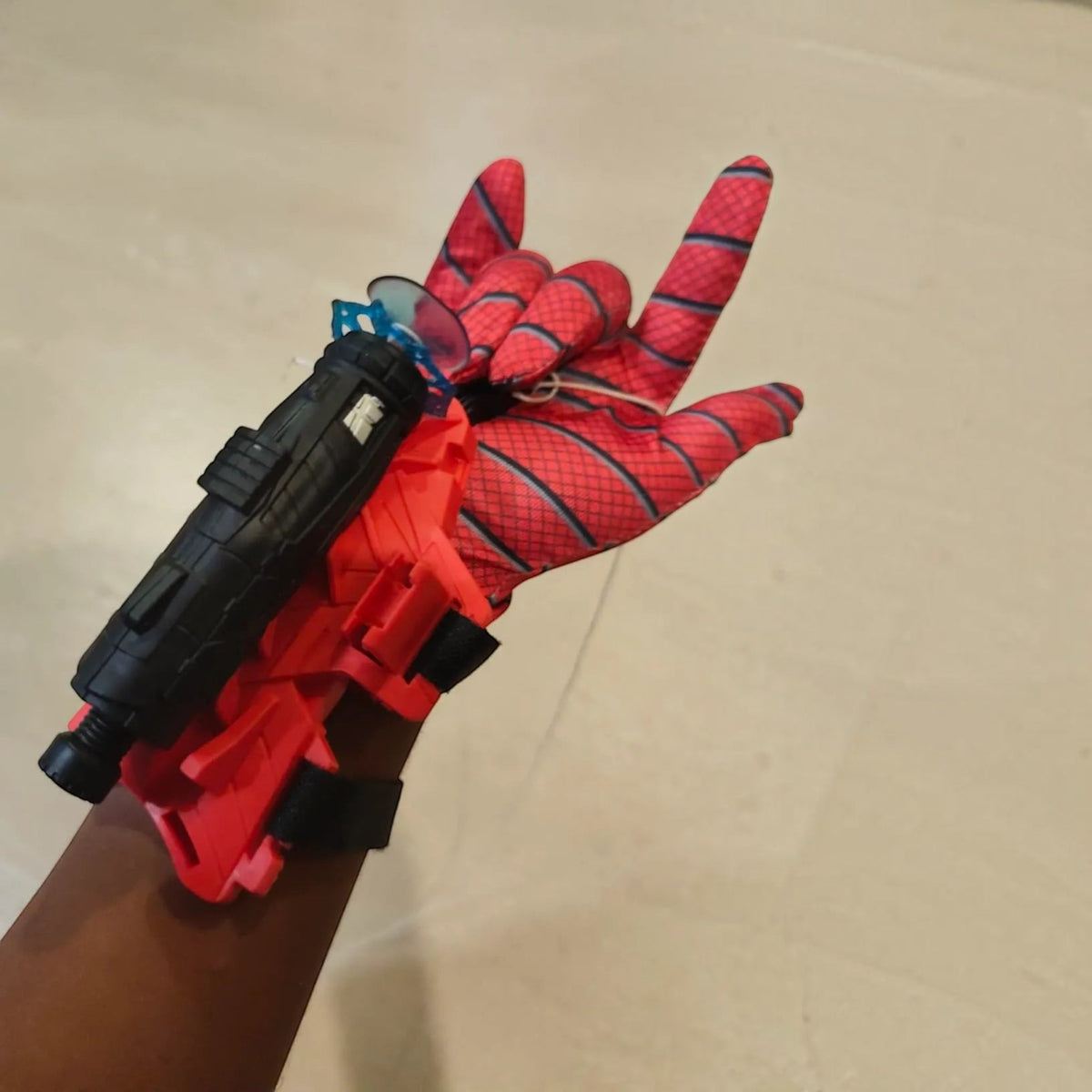 TipTop Retail Spider-Man style red glove with a black wrist-mounted web shooter toy and blue suction cup projectile